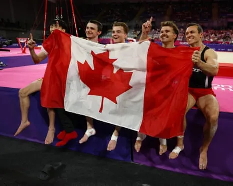 Canada's Ethan Ikeda, William Emard, Felix Dolci, Rene Cournoyer and Jordan Carroll celebrate with their national flag after winning the men's artistic gymnastics final.